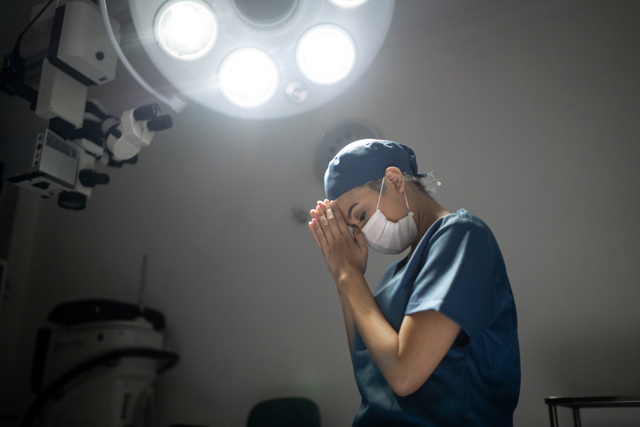 Nurse clasping her hands in prayer