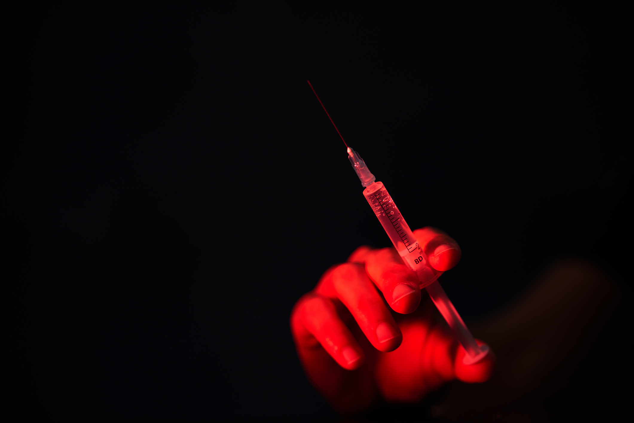 Red hand holding a medical needle